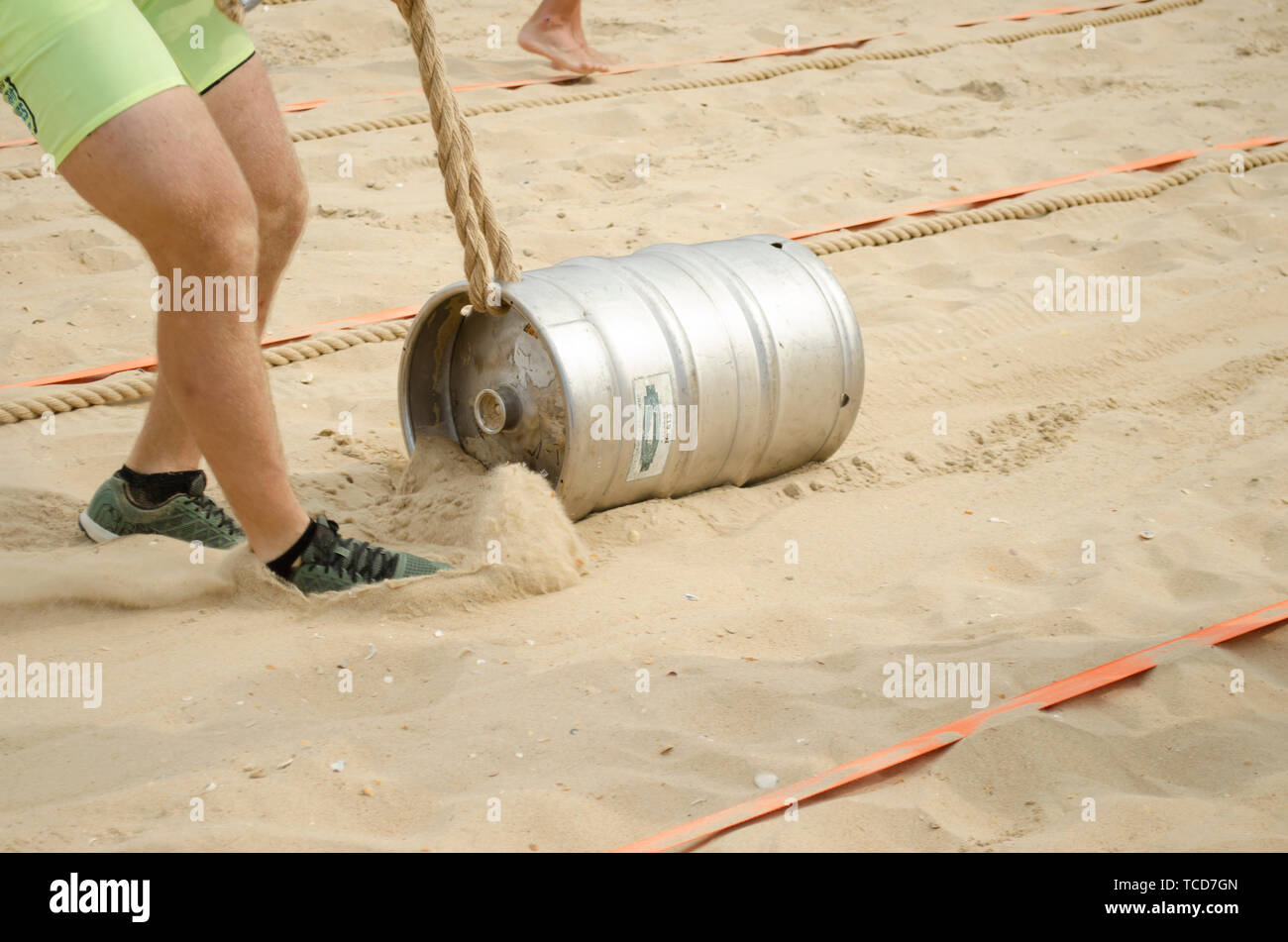 A man in shorts pulls a rope tied with rope over the sand. Sport ...