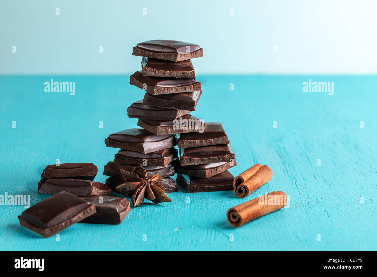 Vertical stacked slices of chocolate, cinnamon stick and star anise on  turquoise background. Stock Photo