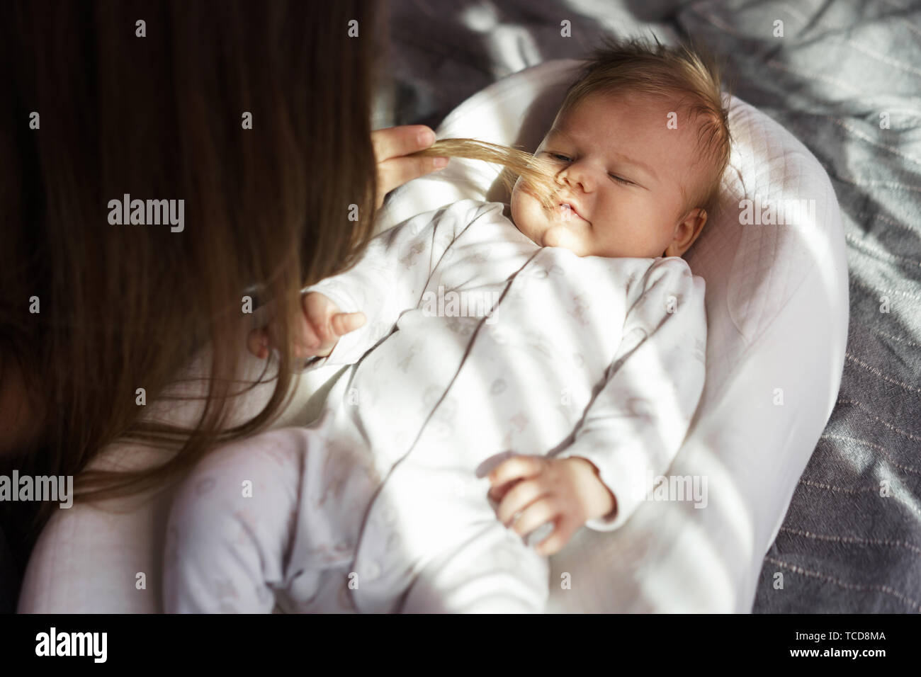 Mother with her newborn son on the bed in the rays of sunlight coming out of the window. Baby