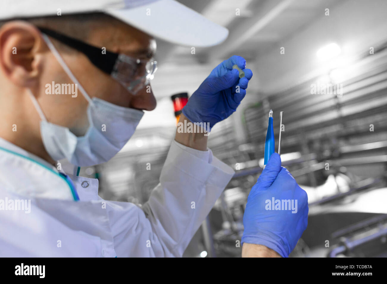 man in a white robe and a cap make an inspection of dairy products Stock Photo