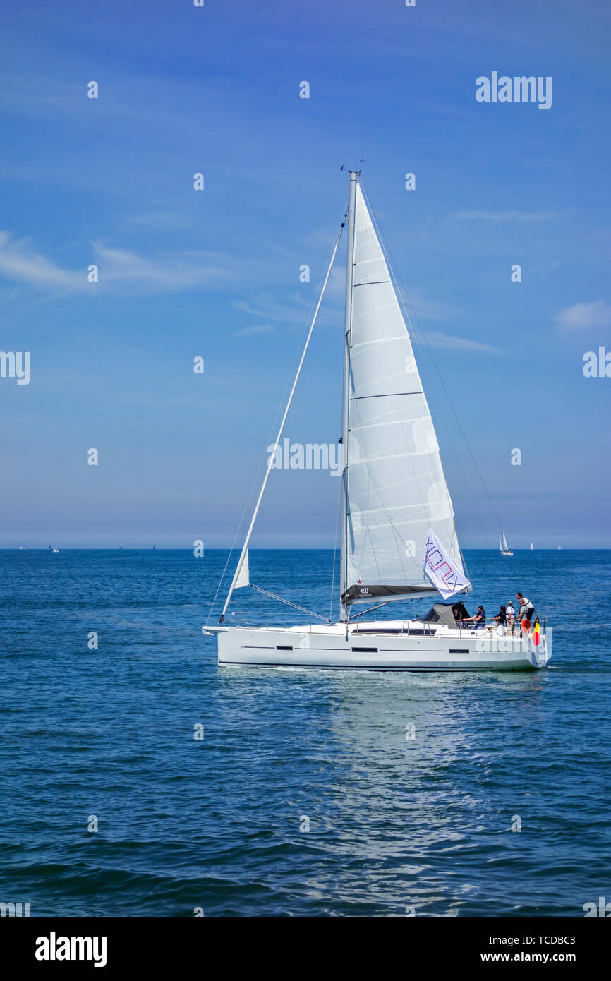 Yachtsmen / sailboat crew hoisting sail while sailing at sea Stock Photo