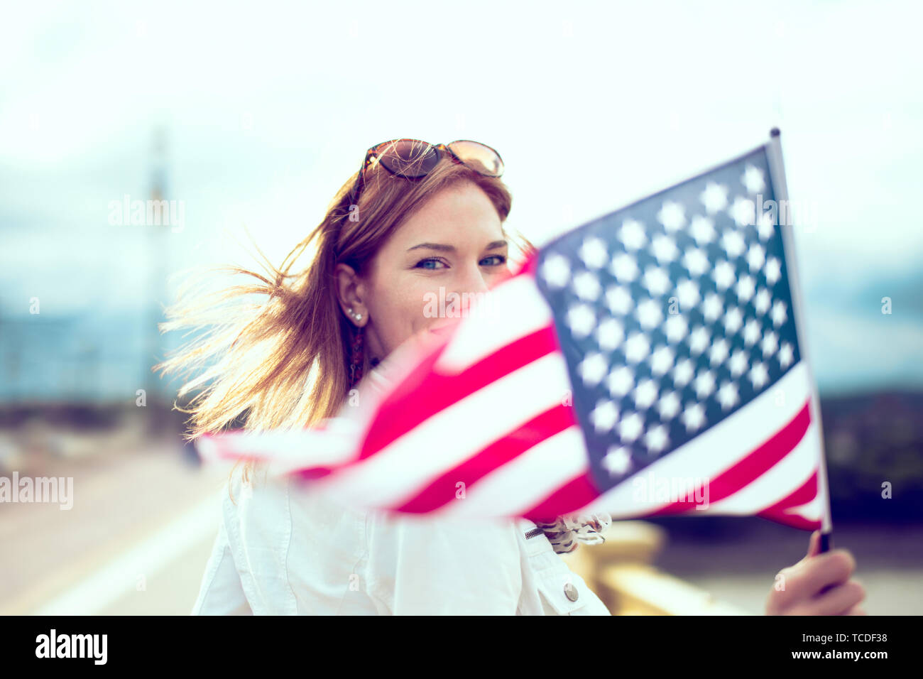Happy young patriot modern urban woman holding USA flag portrait, depth of field, selective focus Stock Photo