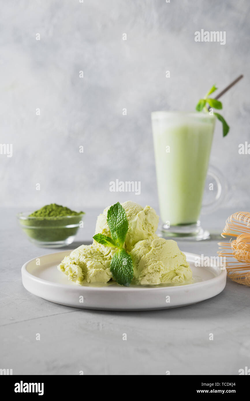 Green matcha ice cream and tea in latte glass on grey table. Close up. Stock Photo
