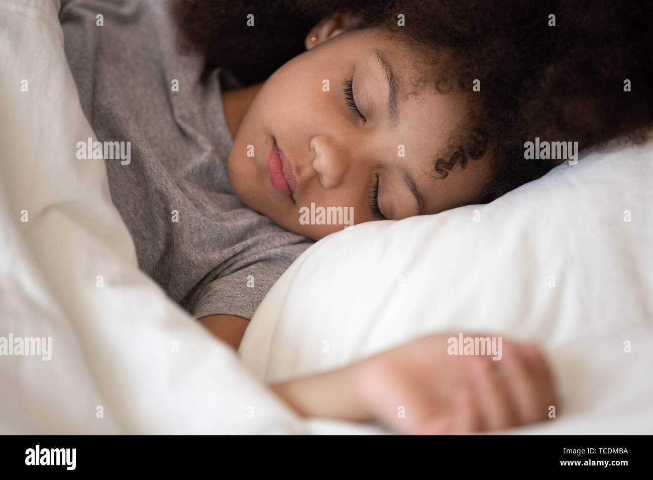 Cute little african american kid girl sleeping alone in bed Stock Photo