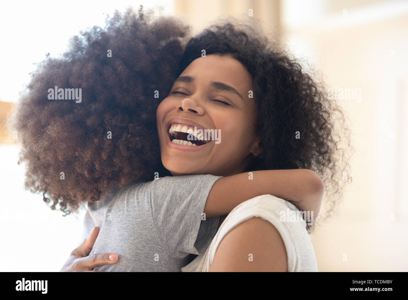 Happy overjoyed african single mother hugging cute little kid daughter Stock Photo