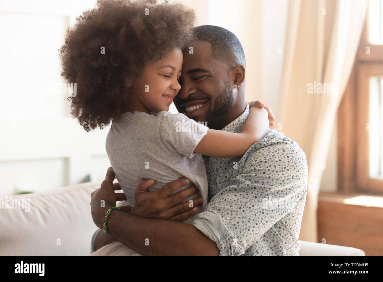 Happy african father holding embracing cute little child daughter Stock Photo