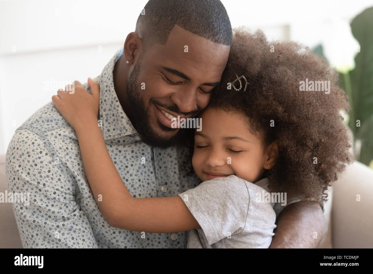 Loving african father hug cute child daughter with eyes closed Stock Photo