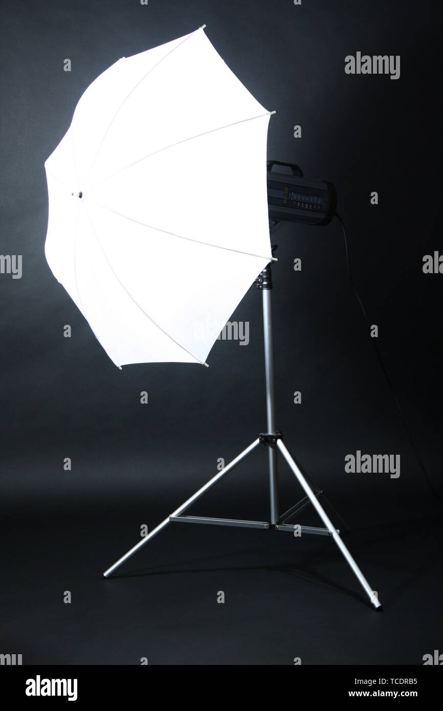 Studio flash with umbrella on grey background Stock Photo