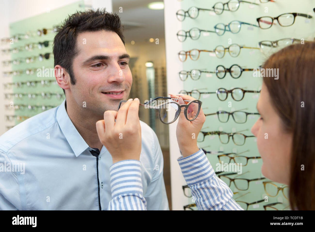 optician fitting eyeglasses to client Stock Photo Alamy