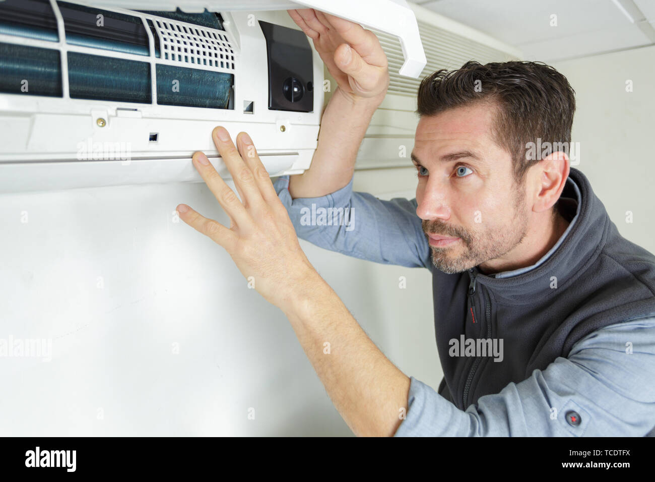 focused handyman testing air conditioning on the wall Stock Photo Alamy