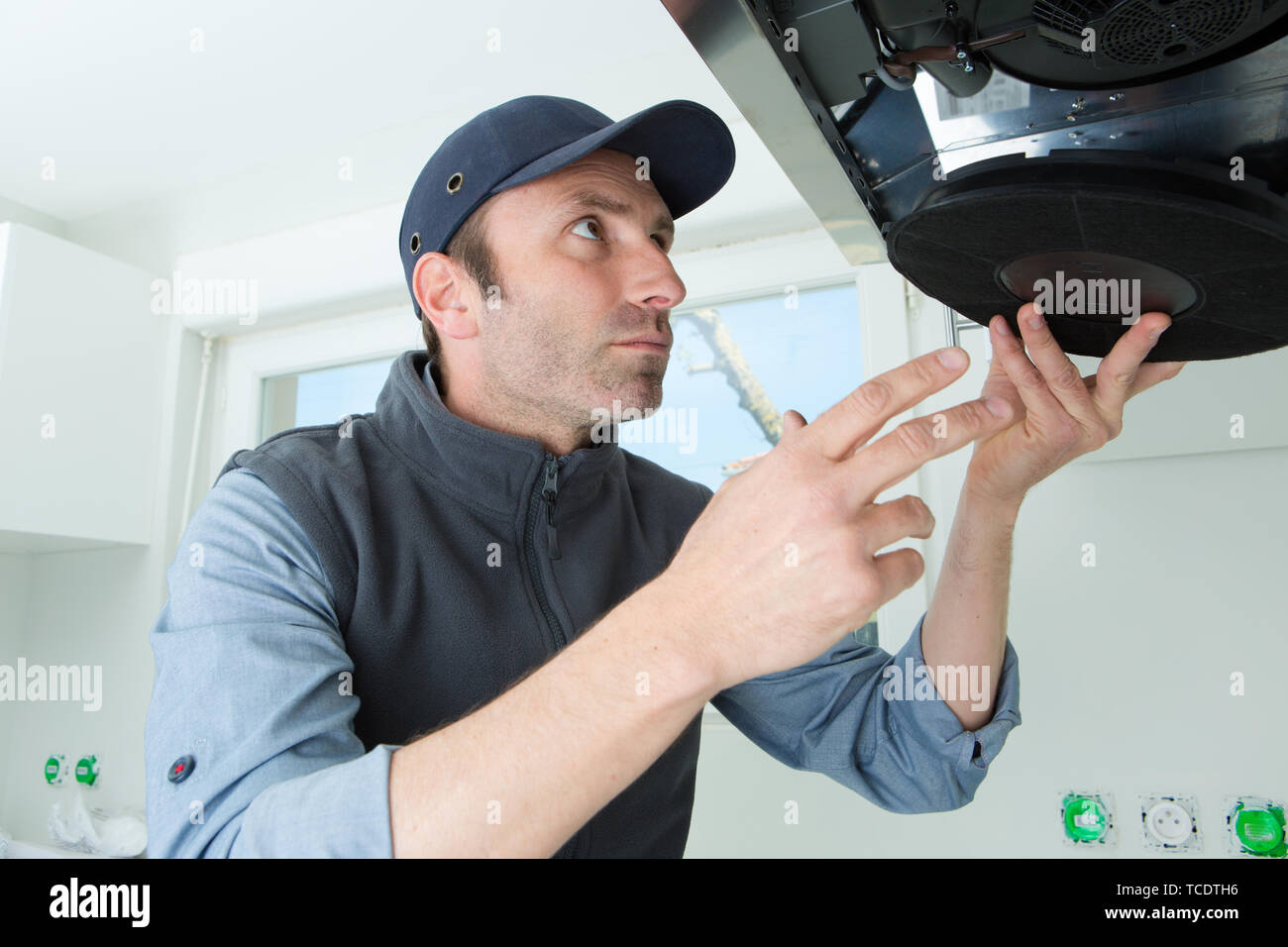 male technician checking kitchen extractor filter with screwdriver Stock Photo