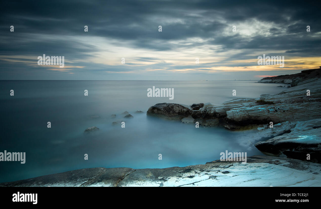 Beautiful sunset on a rocky beach with moving water. Long exposure photography Stock Photo