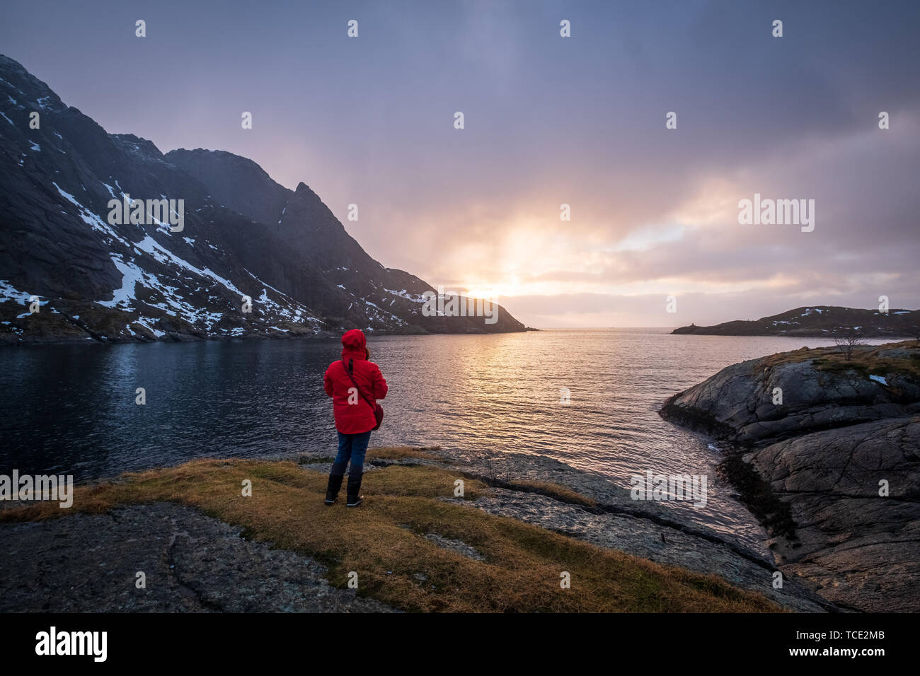 Woman looking at the sunrise, Nusfjord, Lofoten, Nordland, Norway Stock Photo