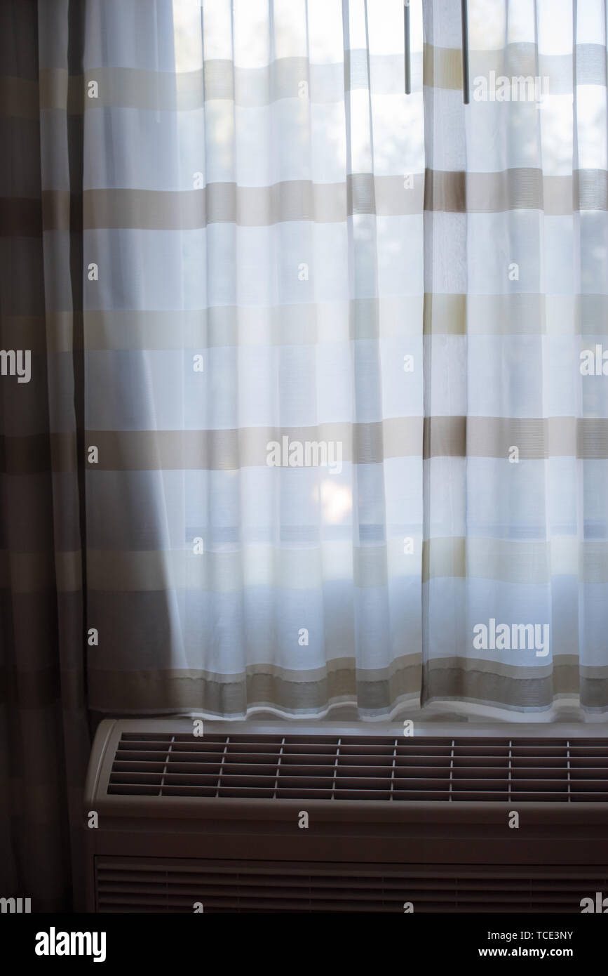 Curtains of pastel colors closing window with radiator below Stock Photo