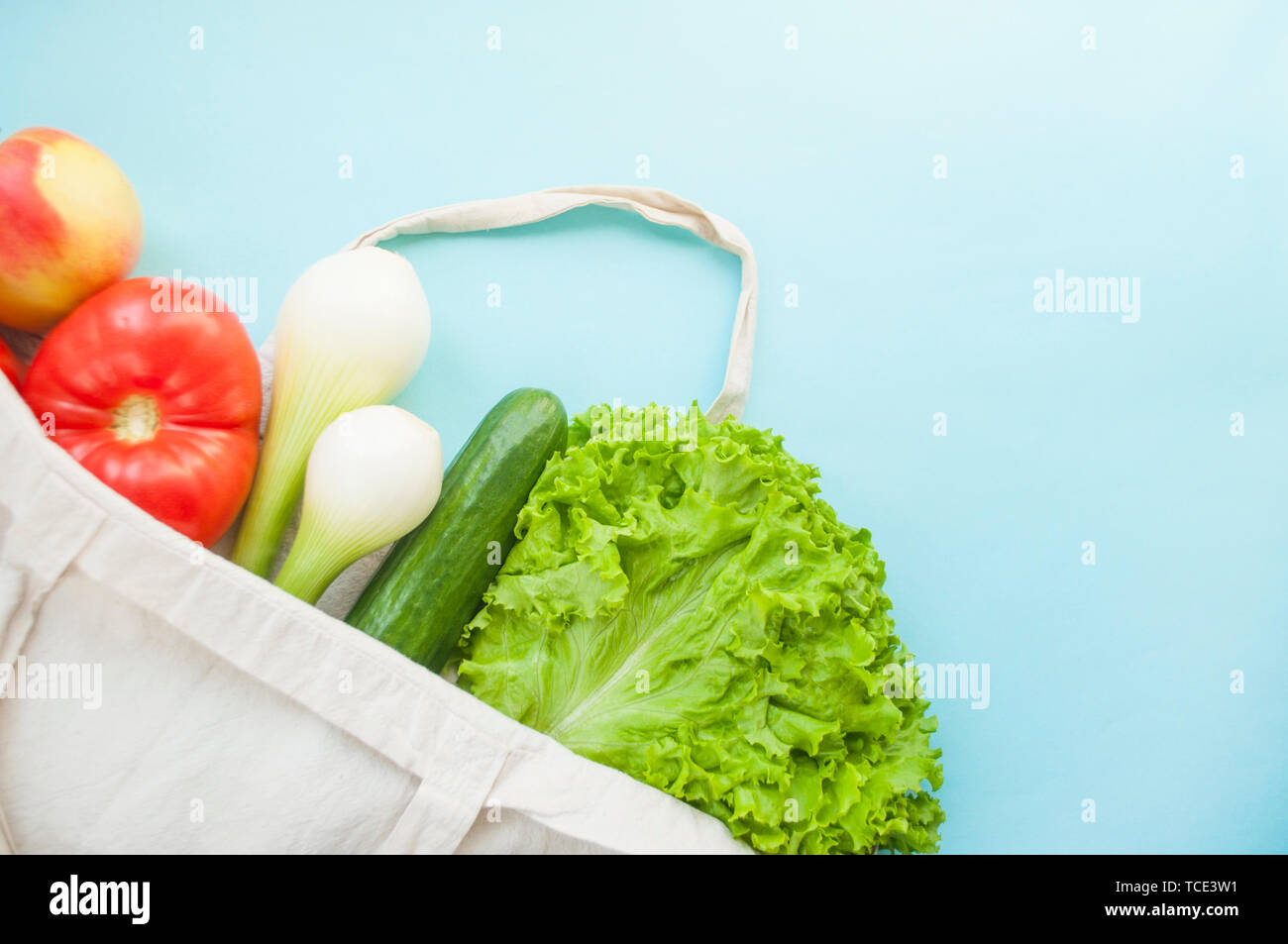 Fresh fruits and vegetables in eco bag on turquoise color background with copyspace. Zero waste concept. Stock Photo