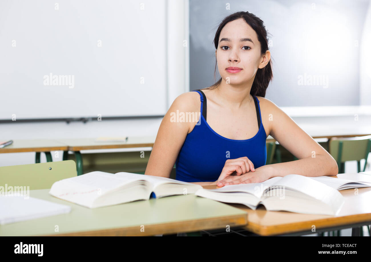 Portrait of smiling schoolgirl who is posing at the desk in the class ...
