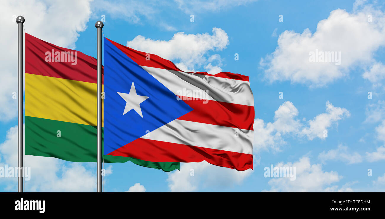 Bolivia and Puerto Rico flag waving in the wind against white cloudy blue sky together. Diplomacy concept, international relations. Stock Photo