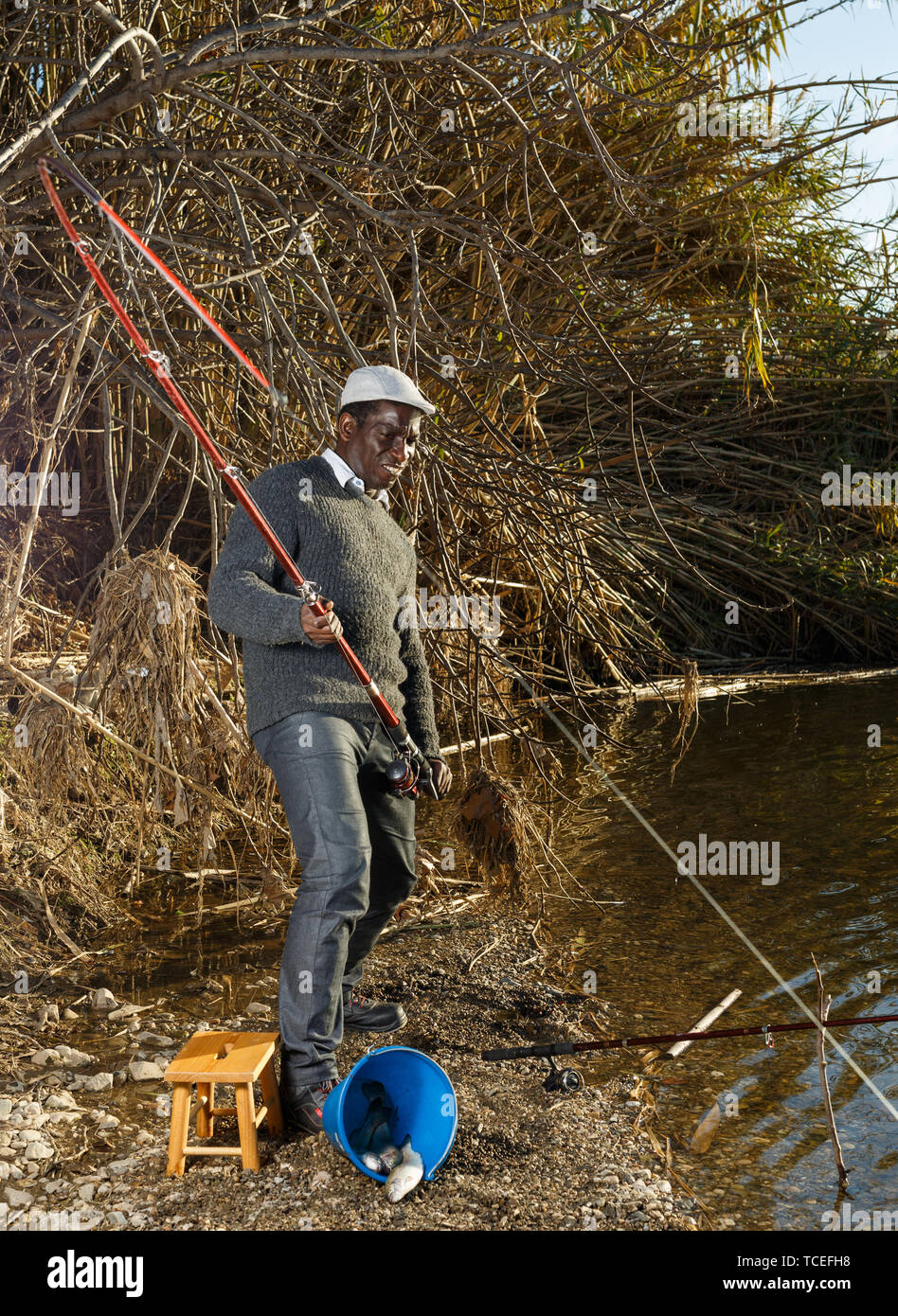 Emotional portrait of African man pulling with rod fish on river Stock Photo