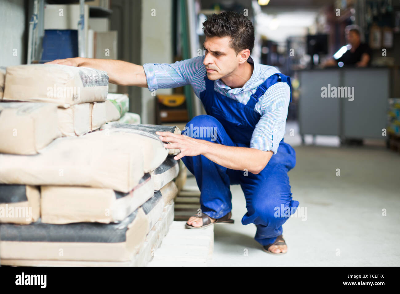 serious male in uniform is choosing cement in the building store room Stock Photo