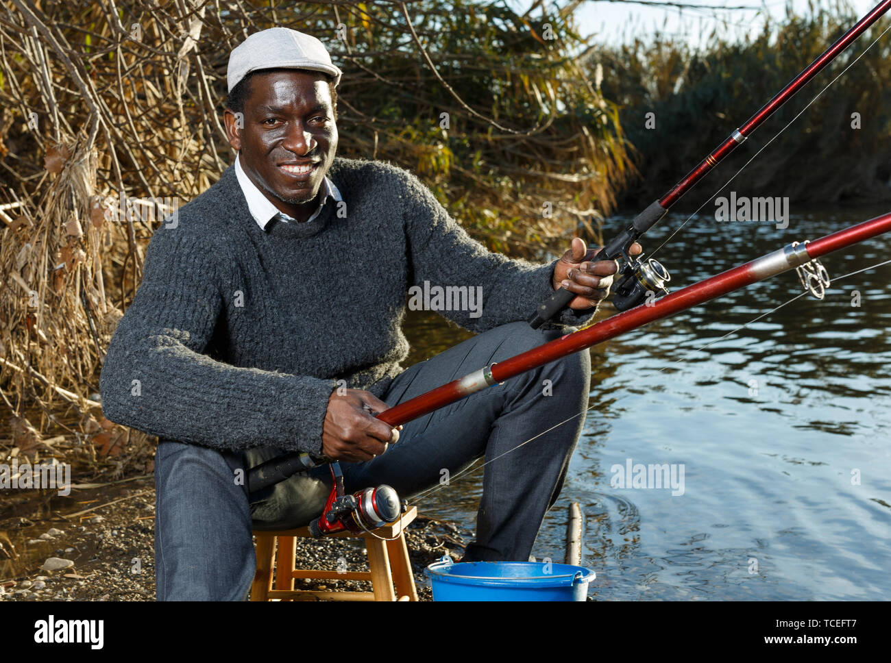 Portrait of friendly African man fishing with rods on river Stock Photo