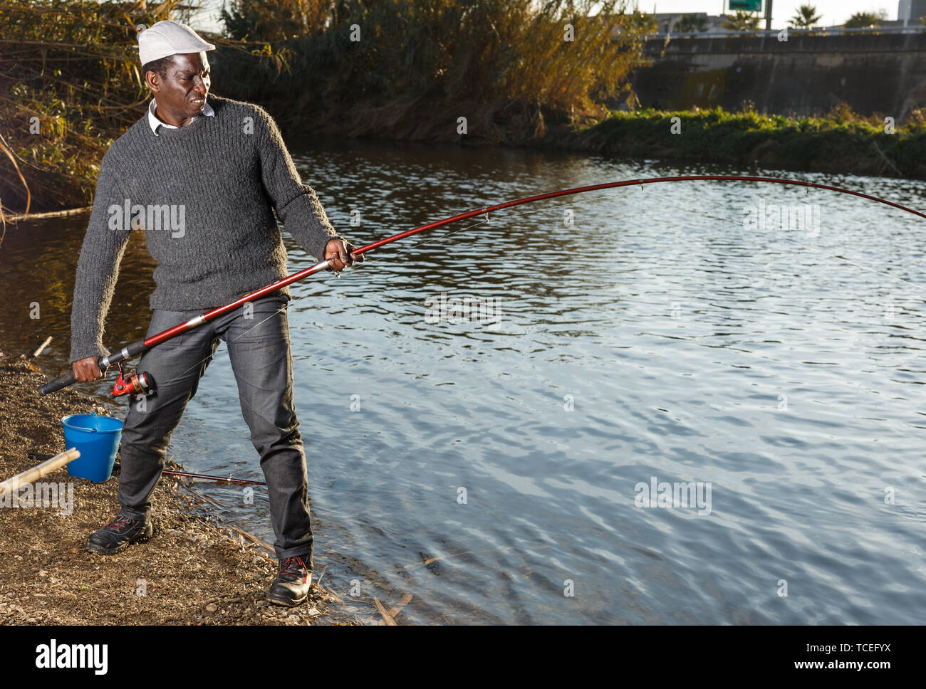 Emotional portrait of African man pulling with rod fish on river Stock Photo