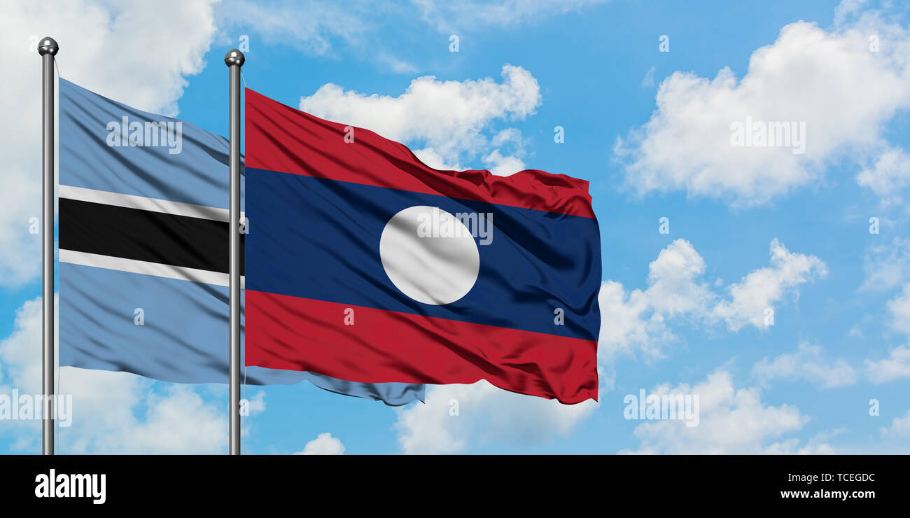 Botswana and Laos flag waving in the wind against white cloudy blue sky ...