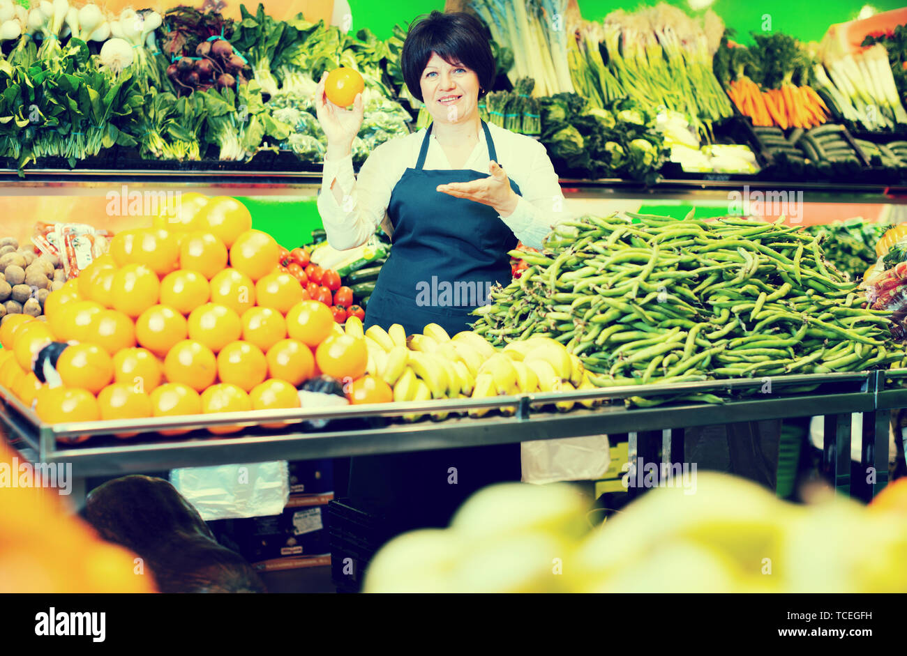 Mature woman offering fresh vegetables and fruits on the market Stock ...