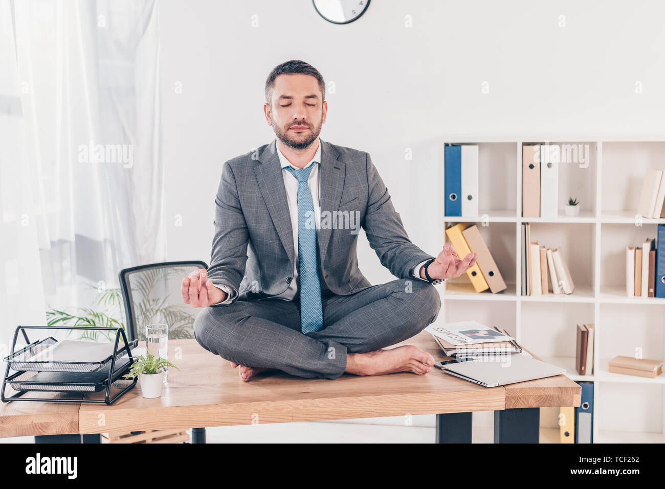 handsome businessman with eyes closed meditating in Lotus Pose on ...