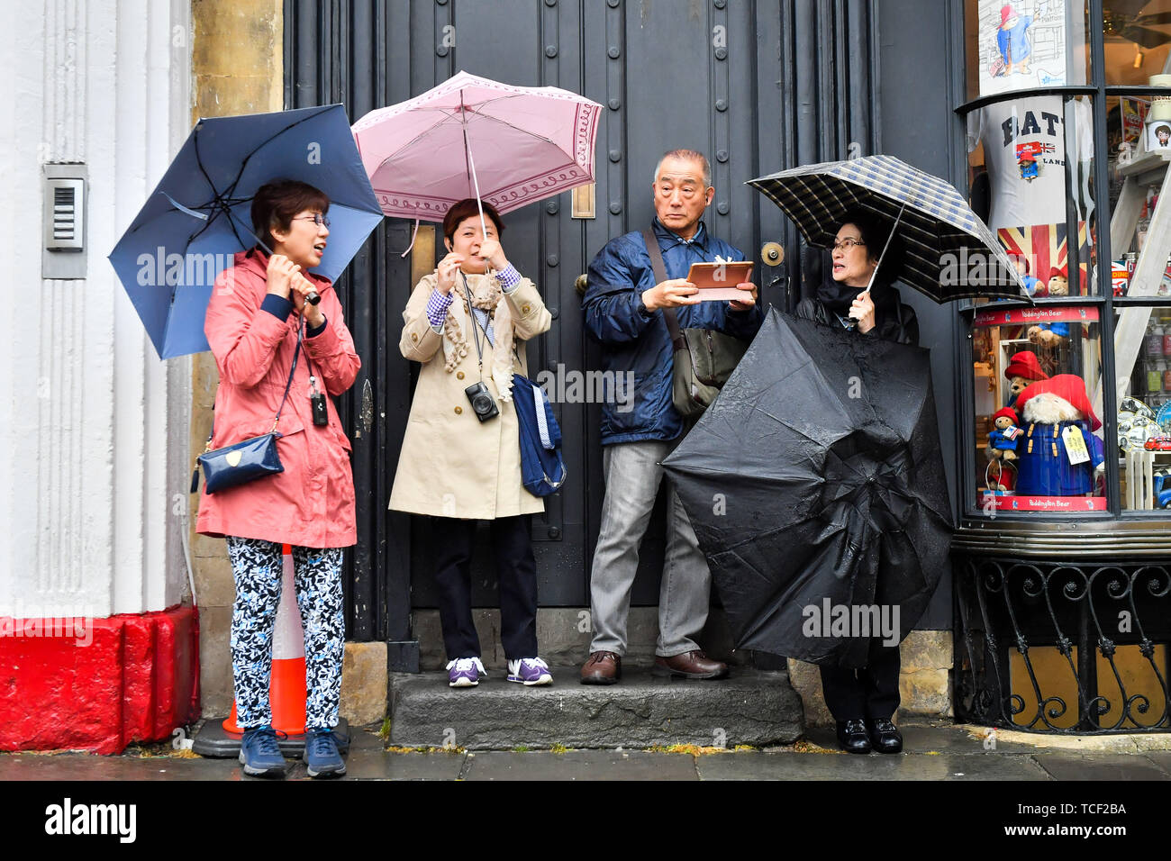 Tourists use umbrellas as they photograph Bath Abbey during a downpour ...