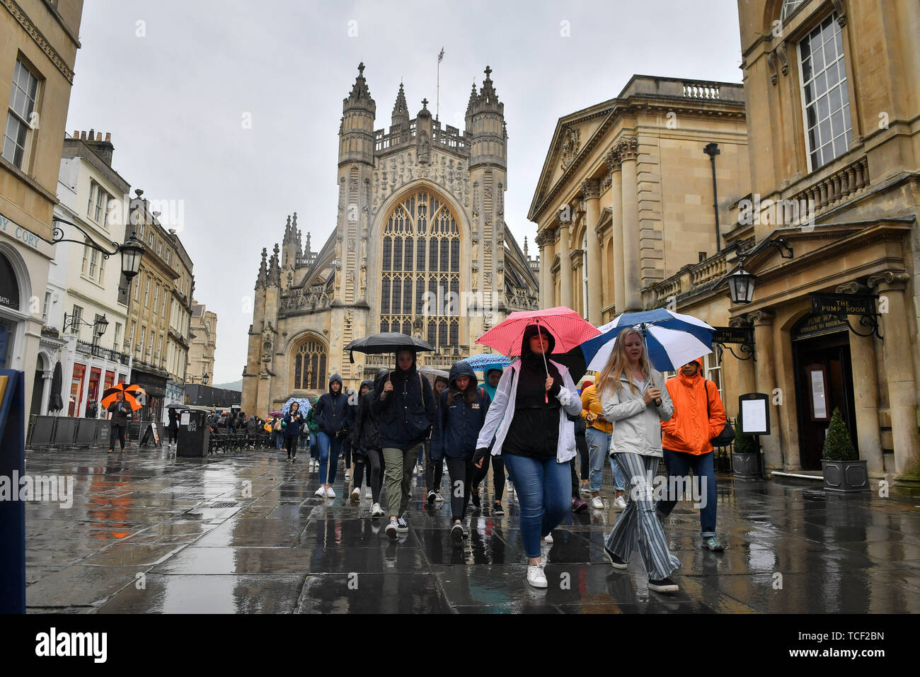 Tourists use umbrellas as they walk across Bath Abbey churchyard during ...