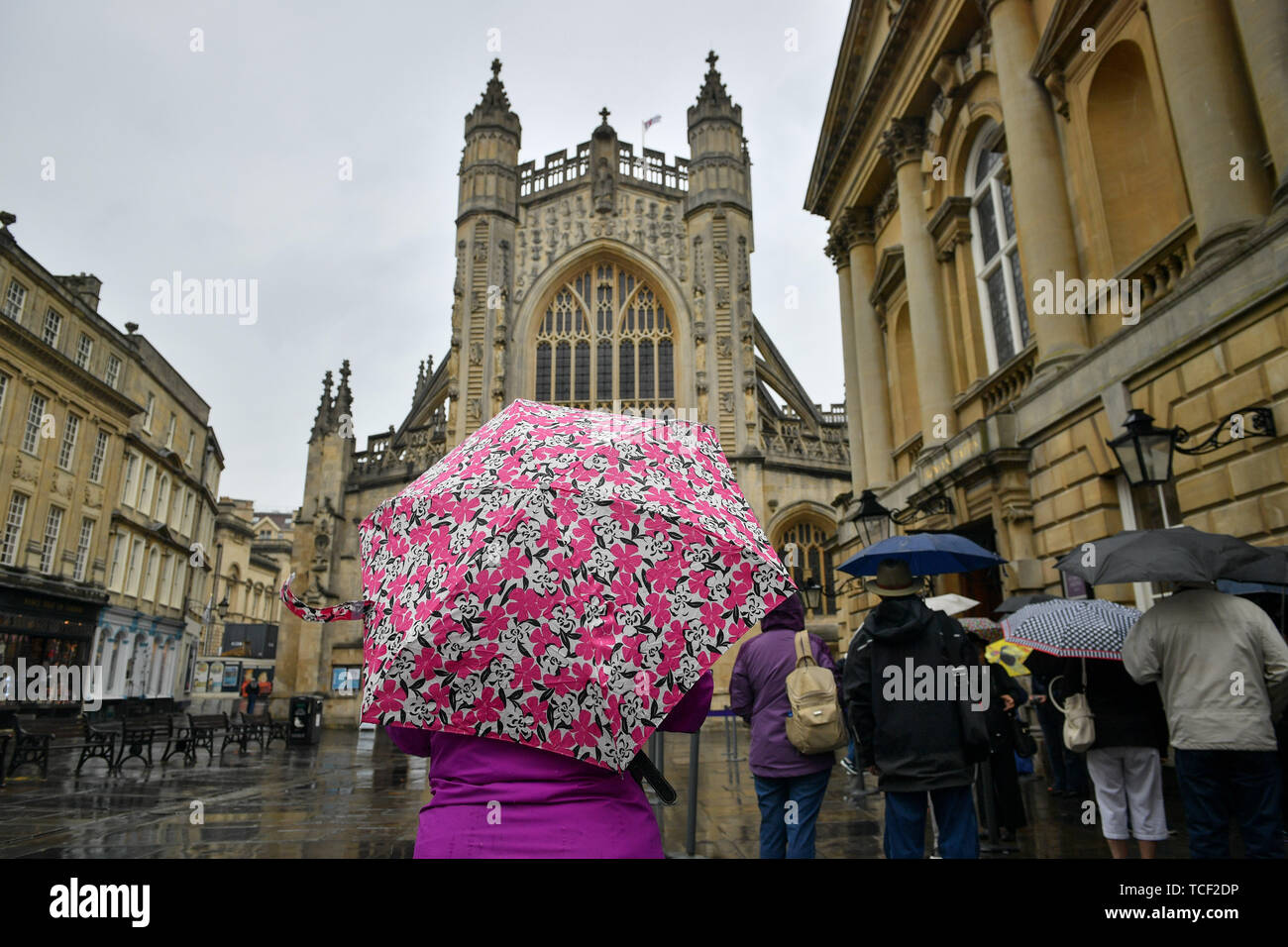 Tourists use umbrellas as they look at Bath Abbey during a downpour in ...