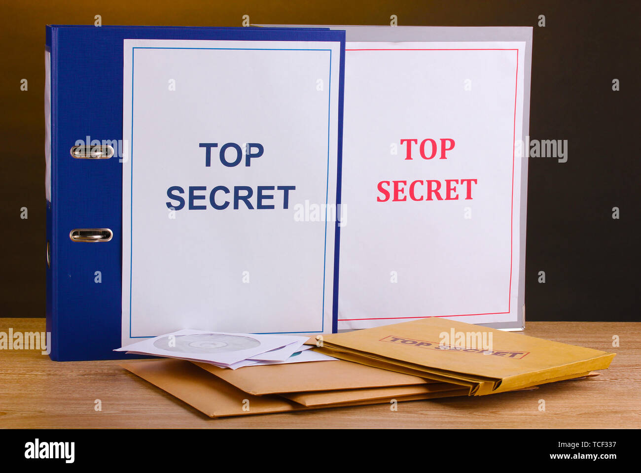 Envelopes and folders with top secret stamp and  CD disks on wooden table on brown background Stock Photo