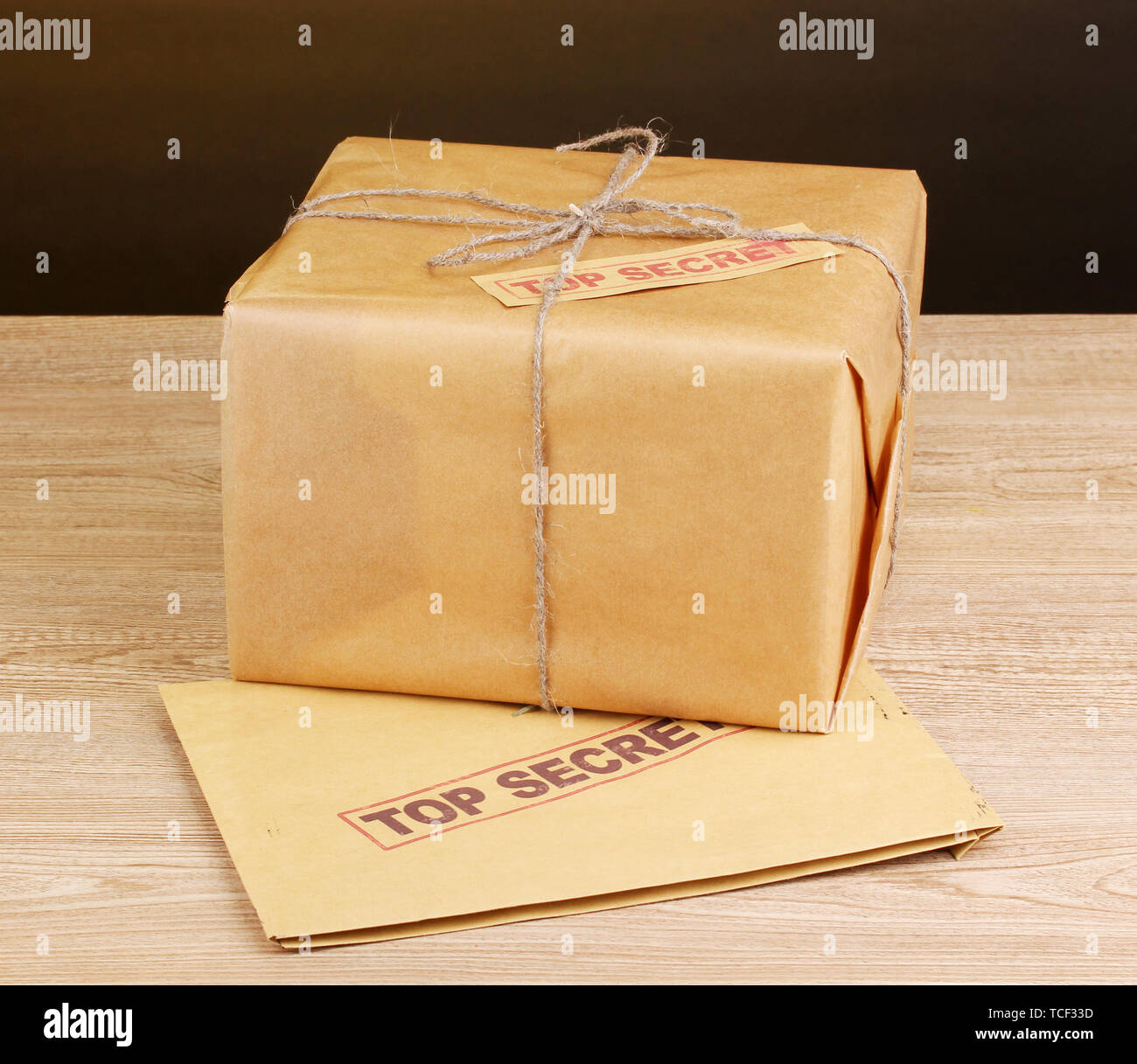 Parcel and envelope with top secret stamp on wooden table on brown background Stock Photo