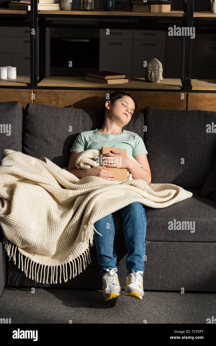 boy with book sleeping under blanket in living room Stock Photo Alamy