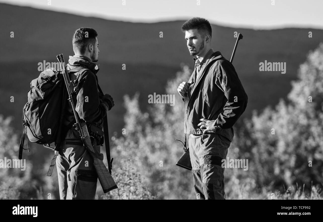 Friendship of men hunters. Military uniform fashion. Army forces. Camouflage. Hunting skills and weapon equipment. How turn hunting into hobby. Man hunters with rifle gun. Boot camp. Illegal business. Stock Photo