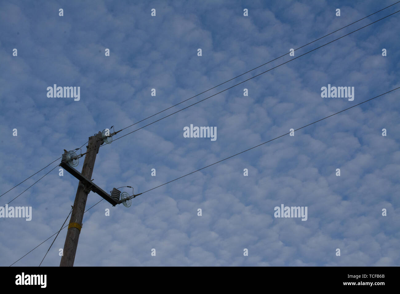 Electric pole with wires on background of blue sky full of white ...