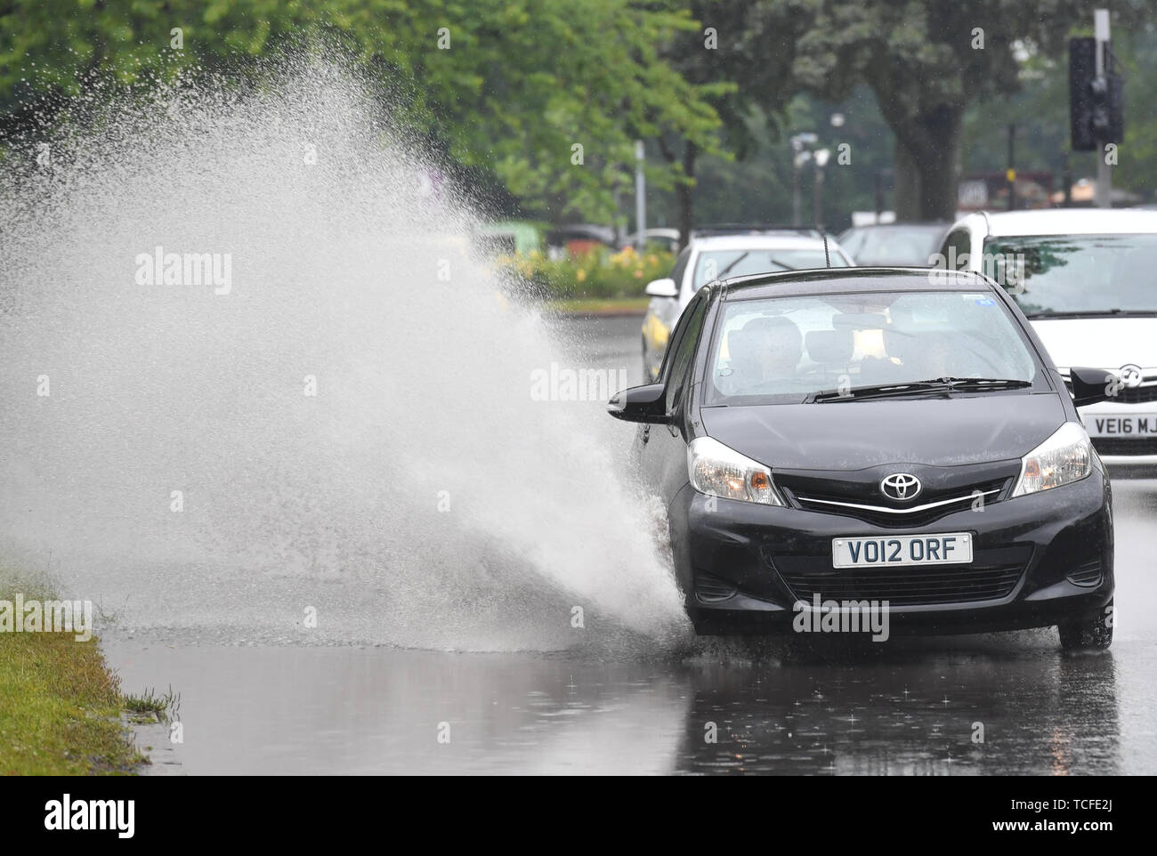 Car is driven through large puddle in hale green hires stock