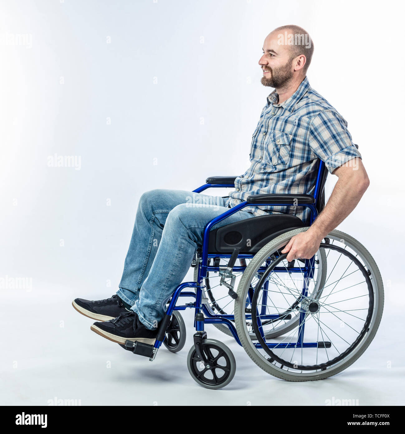 Smiling disabled man sitting in a wheelchair. Positive expression and casual clothes. Stock Photo