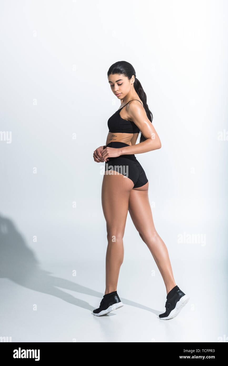 beautiful athletic african american girl in black sports bra, shorts and  sneaker on white background Stock Photo - Alamy