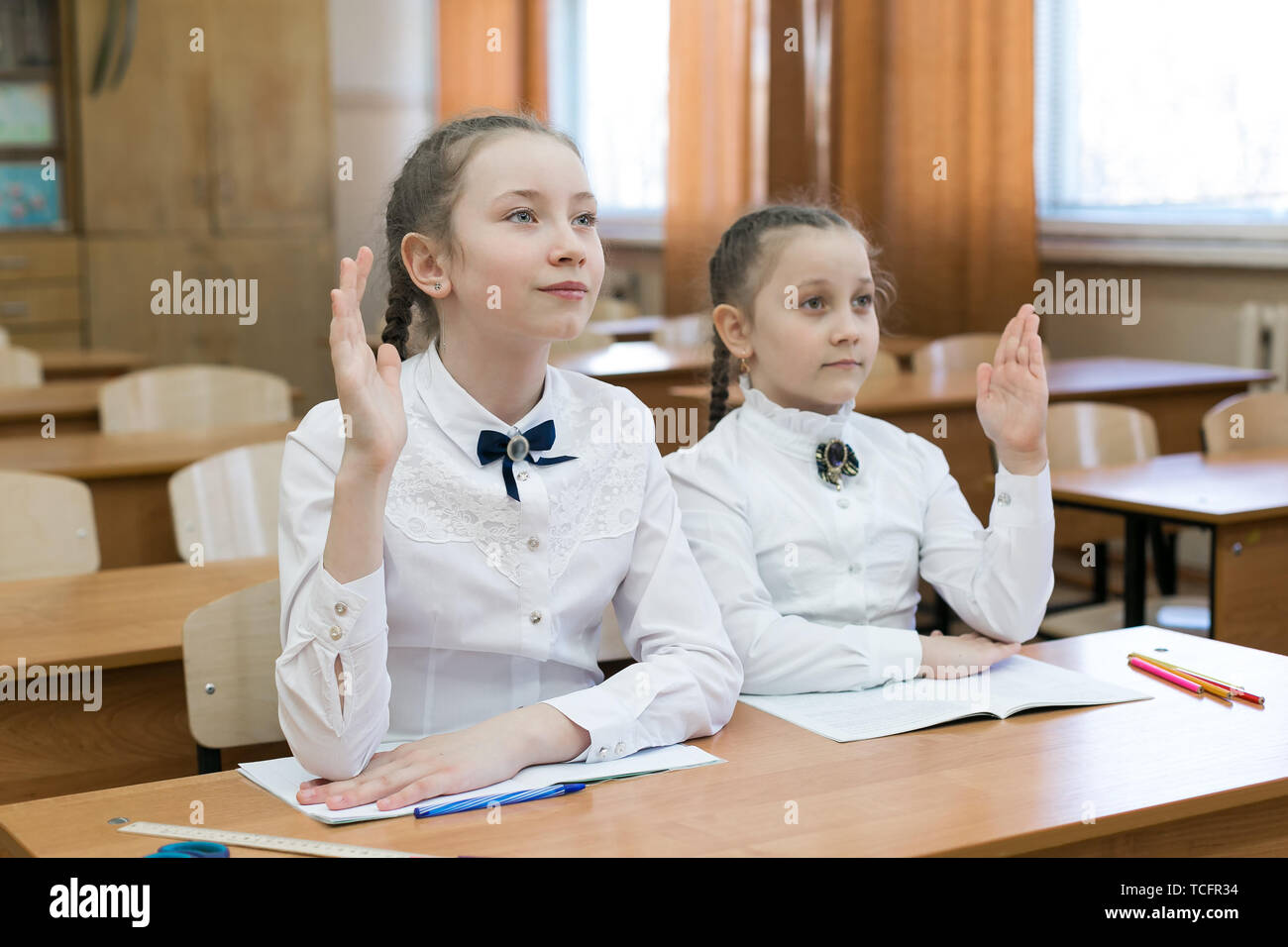 The schoolgirl girl raises her hand to answer the teacher's question ...