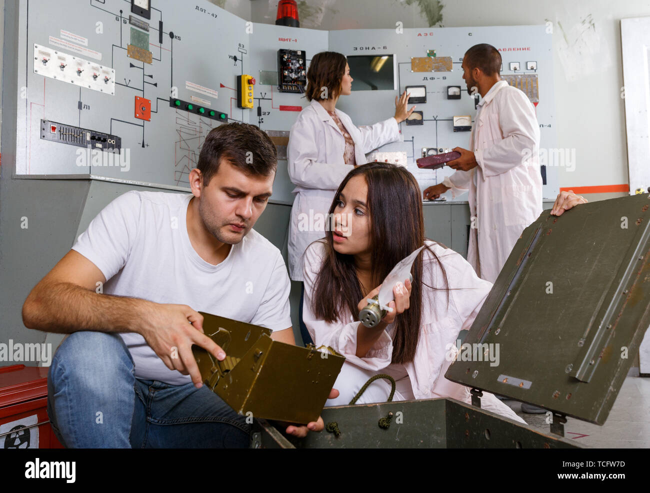 Group Inspecting Box Young friends solving conundrum in quest room in view as closed nuclear ...