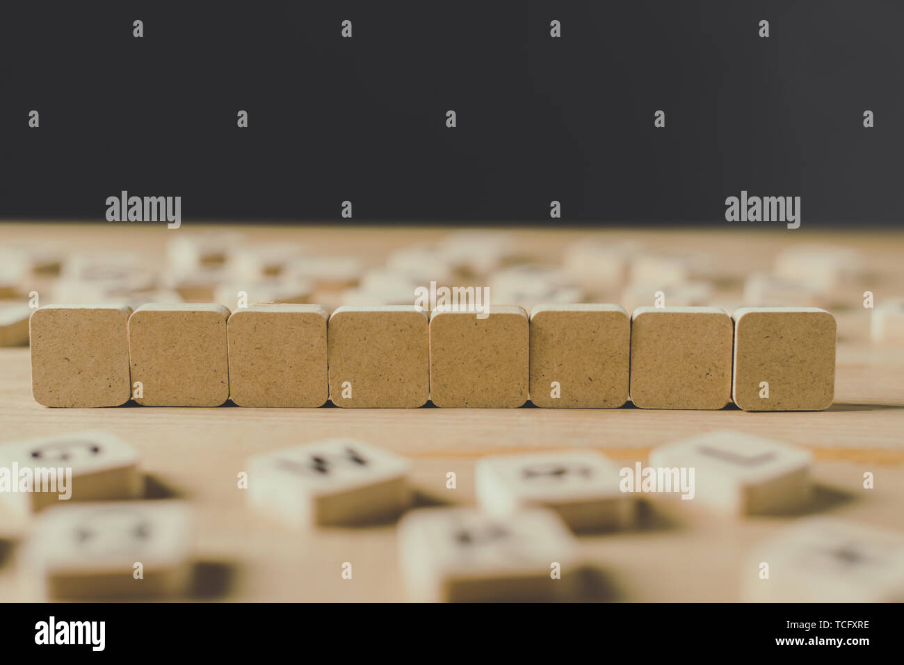 selective focus of eight empty cubes surrounded by blocks with letters ...