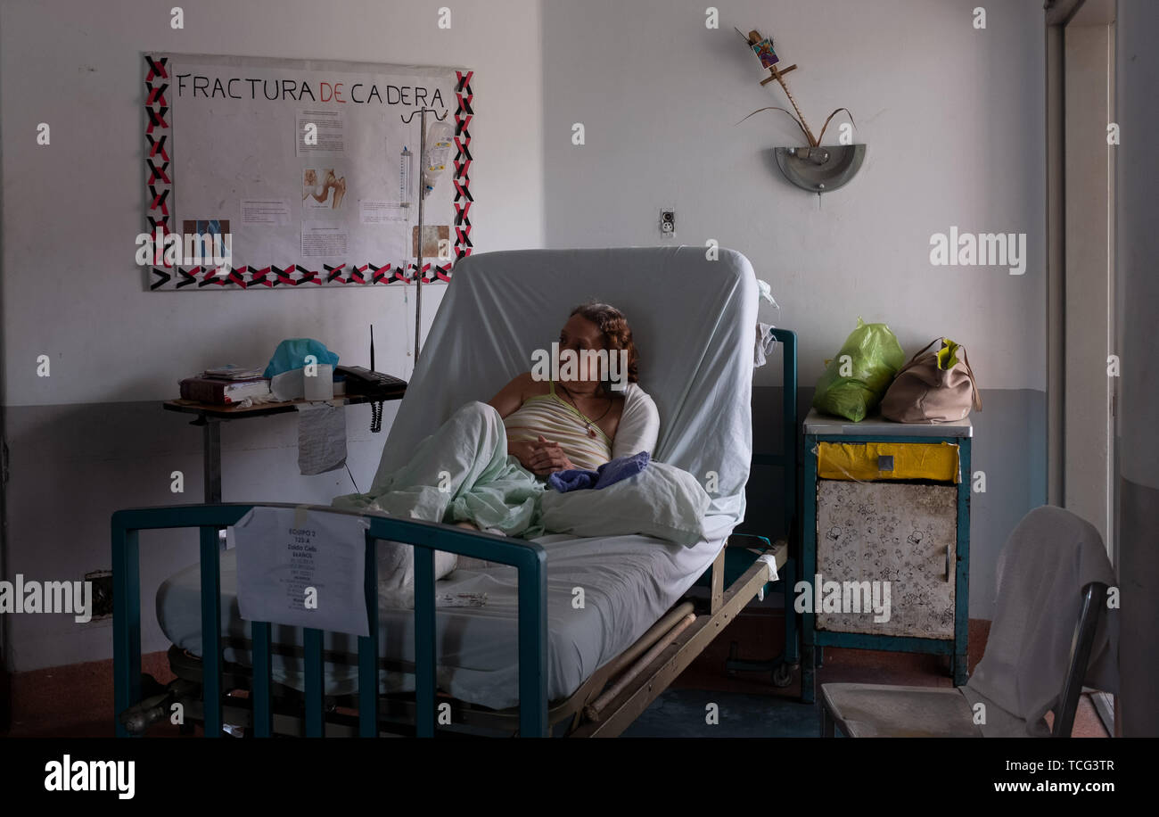 Caracas, Venezuela. 7th June, 2019. A woman sits in her bed in the Hospital ClÃ-nico Universitari in Caracas Venezuela. She has multiple traumatic fractures including her hip and upper arm. She has been waiting 2 months for surgery. She cannot get out of bed. Credit: Allison Dinner/ZUMA Wire/Alamy Live News Stock Photo