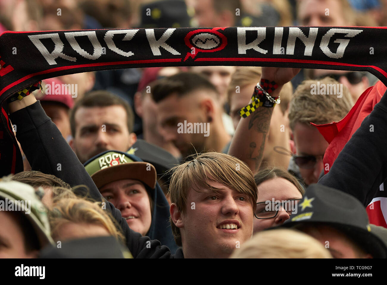 08 June 2019, Rhineland-Palatinate, Nürburg: A visitor holds a scarf with the inscription 'Rock am Ring' in front of the main stage of the open-air festival 'Rock am Ring'. On three days about 75 bands will perform on three stages in front of more than 80 000 spectators. Photo: Thomas Frey/dpa Stock Photo