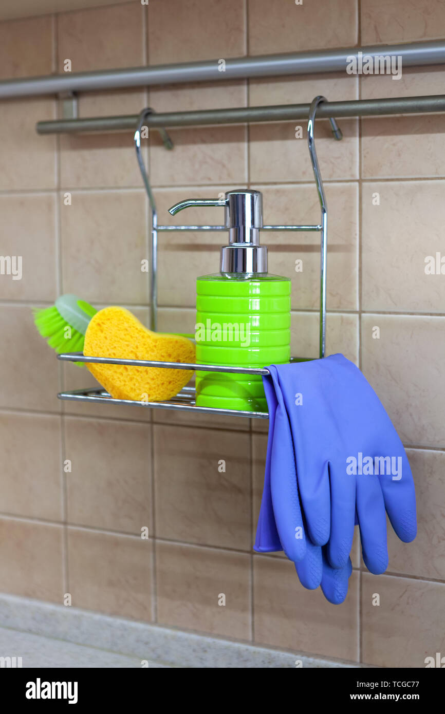 Utensils for washing dishes, liquid, gloves, brush, sponge on metal shelf in kitchen. Concept of decanting detergents, no labels and visual noise. Stock Photo