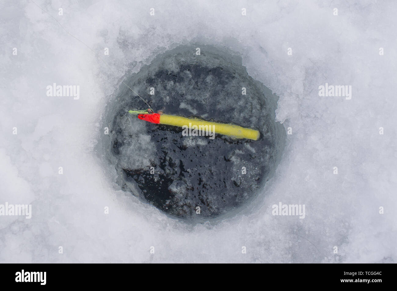 Ice fishing hole in ice with bobber Stock Photo Alamy
