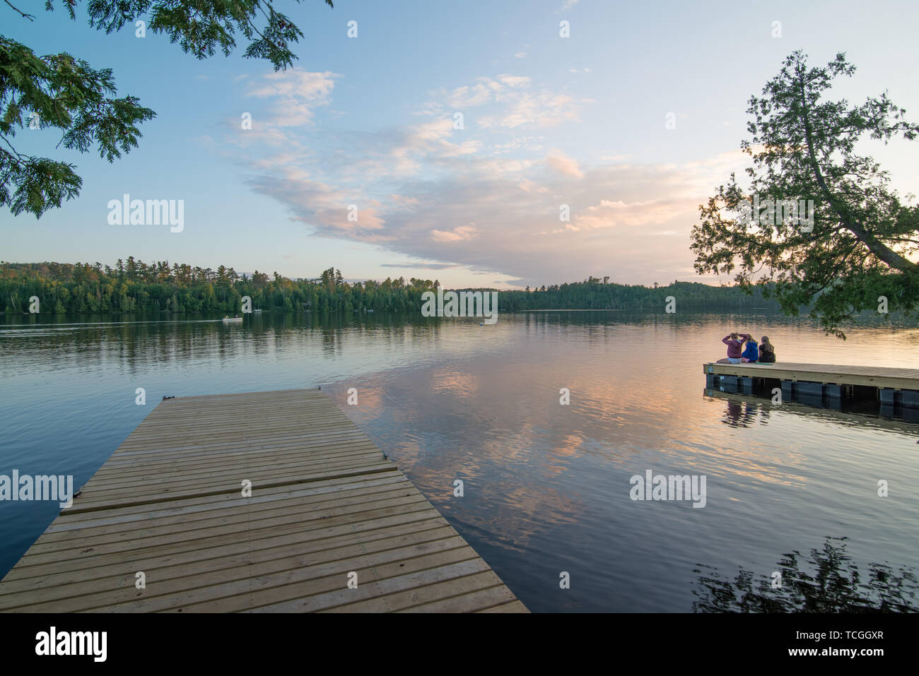 Beautiful sunset taken off a dock on Hungry Jack Lake off the Gunflint Trail in Northern Minnesota with group of people on a dock (no faces visible) Stock Photo