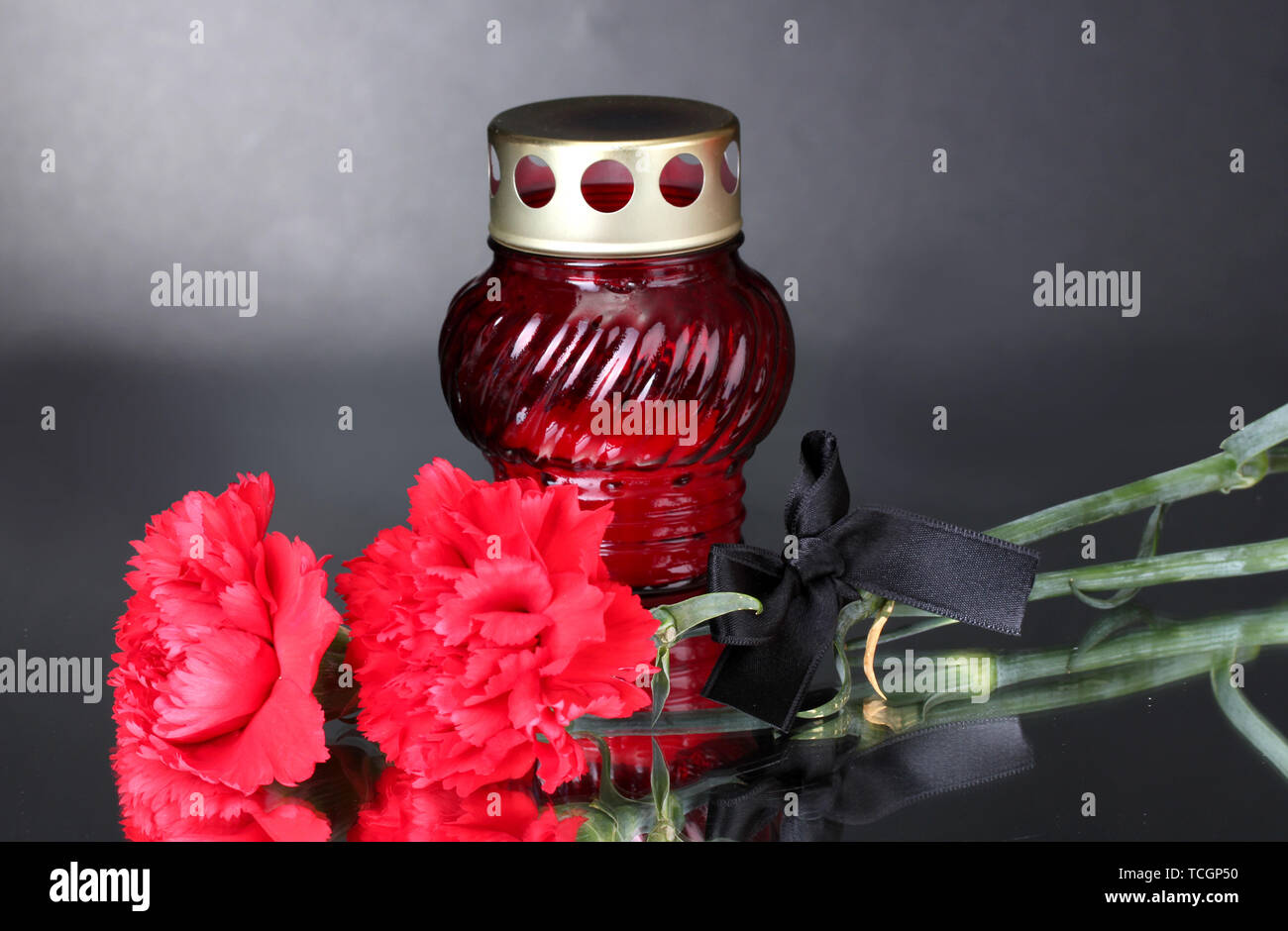Memory lantern with candle, carnations and black ribbon on grey background Stock Photo