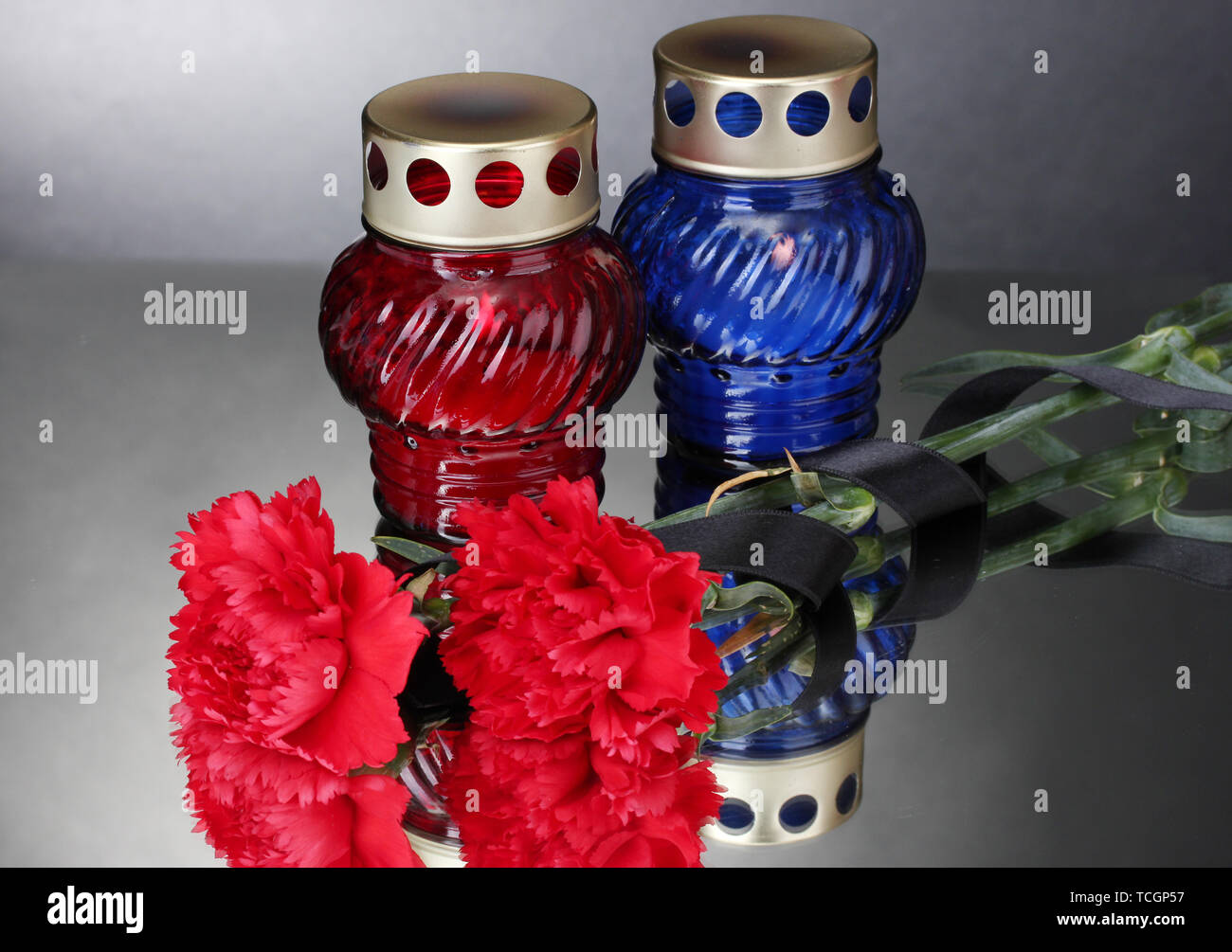 Memory lanterns with candles,  carnations and black ribbon on grey background Stock Photo