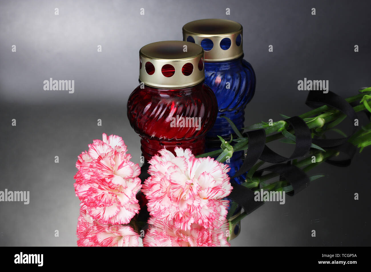 Memory lanterns with candles,  carnations and black ribbon on grey background Stock Photo